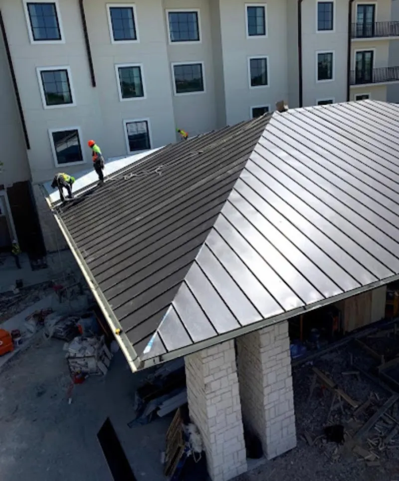 Crew installing standing seam metal roof panels on a commercial project in Leesburg